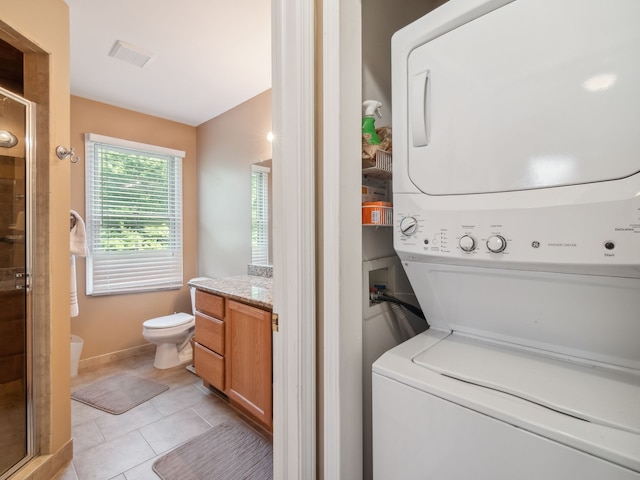 laundry area with visible vents, stacked washer / dryer, and light tile patterned flooring