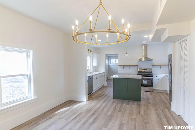 kitchen featuring stainless steel appliances, backsplash, light wood-style floors, a kitchen island, and wall chimney exhaust hood