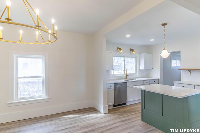 kitchen with light wood finished floors, white cabinets, dishwasher, light countertops, and a sink