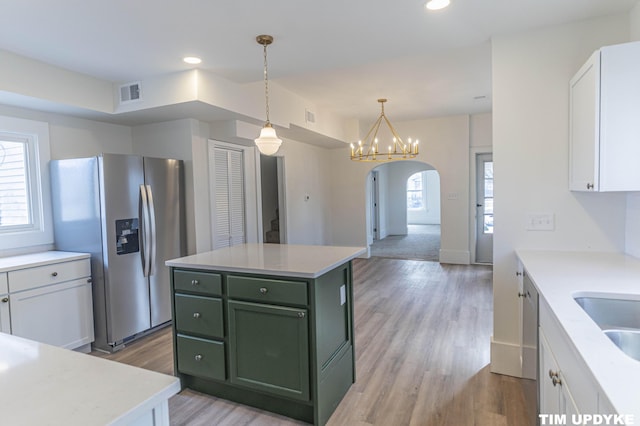 kitchen with arched walkways, visible vents, white cabinets, green cabinetry, and stainless steel fridge with ice dispenser