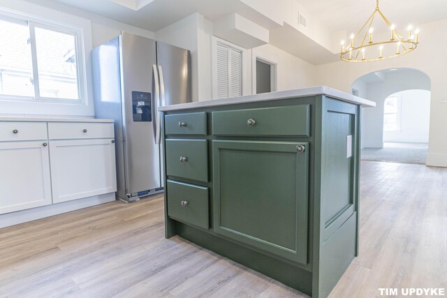 kitchen with stainless steel fridge, visible vents, arched walkways, light wood-style flooring, and green cabinetry