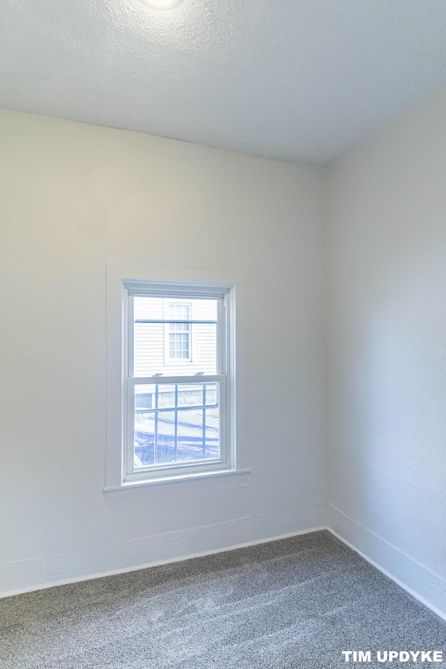 carpeted empty room with baseboards and a textured ceiling