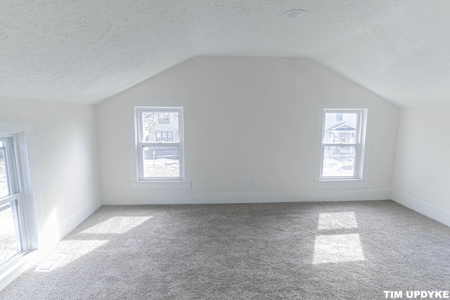 bonus room featuring a wealth of natural light, carpet, vaulted ceiling, and a textured ceiling