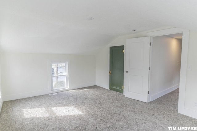 additional living space featuring vaulted ceiling, carpet flooring, visible vents, and baseboards