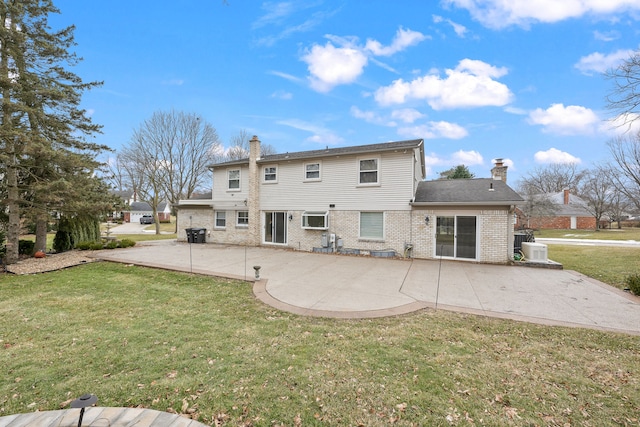 back of property featuring a patio area, a chimney, a lawn, and brick siding