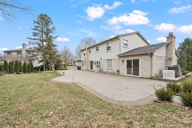 back of house with a patio, cooling unit, brick siding, a yard, and a chimney