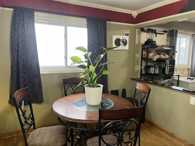 dining space featuring crown molding, baseboards, and wood finished floors