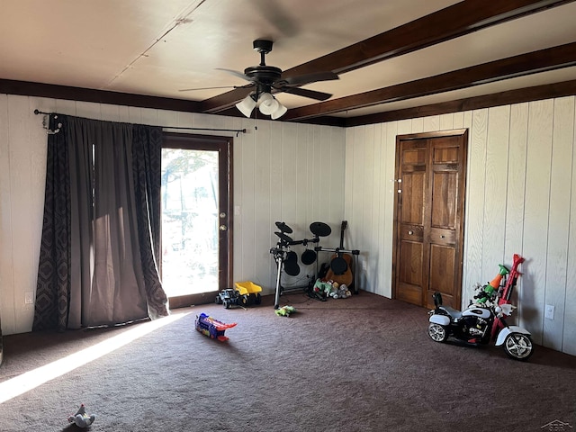 playroom with carpet, a ceiling fan, and beamed ceiling