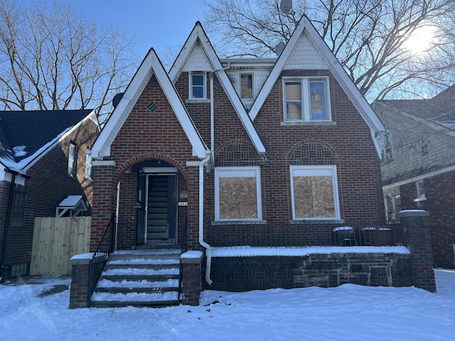 tudor house featuring brick siding and fence