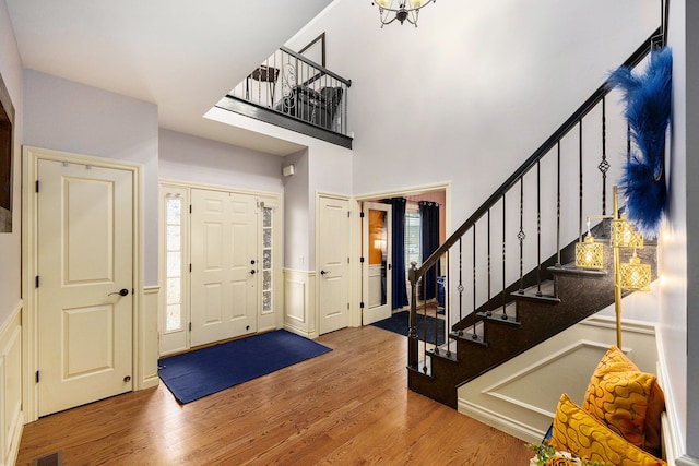 foyer entrance featuring a wainscoted wall, stairway, wood finished floors, and visible vents