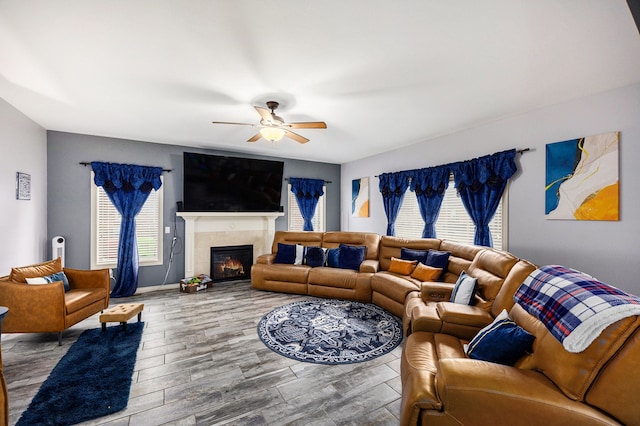 living area featuring a ceiling fan, wood finished floors, a wealth of natural light, and a tile fireplace