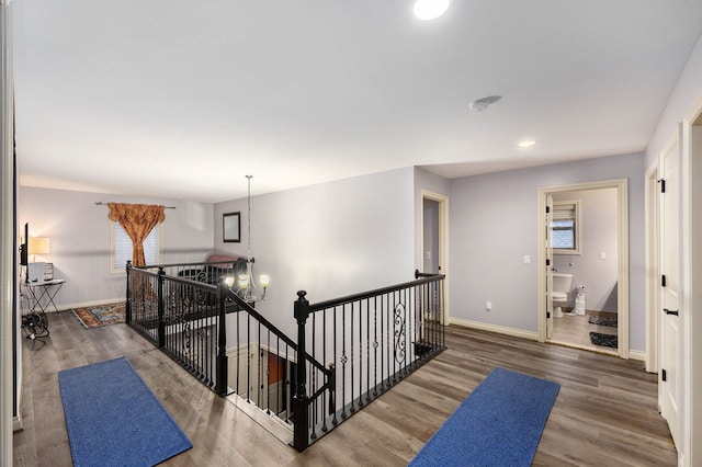 hall with recessed lighting, an inviting chandelier, an upstairs landing, wood finished floors, and baseboards