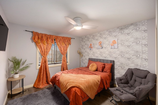 bedroom featuring a ceiling fan, wallpapered walls, baseboards, and wood finished floors