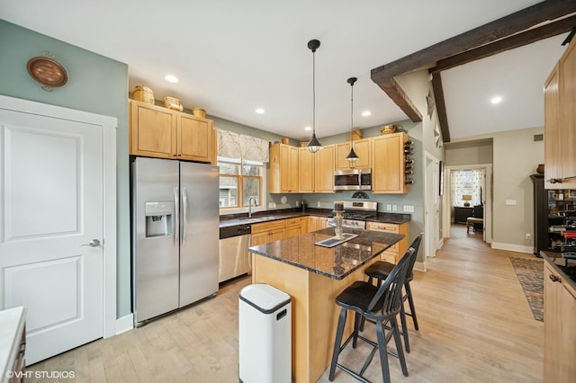 kitchen with a breakfast bar area, a sink, appliances with stainless steel finishes, light wood-type flooring, and light brown cabinetry