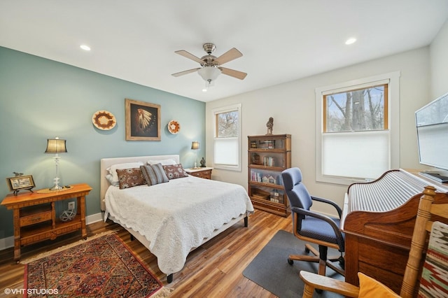 bedroom with ceiling fan, multiple windows, wood finished floors, and baseboards