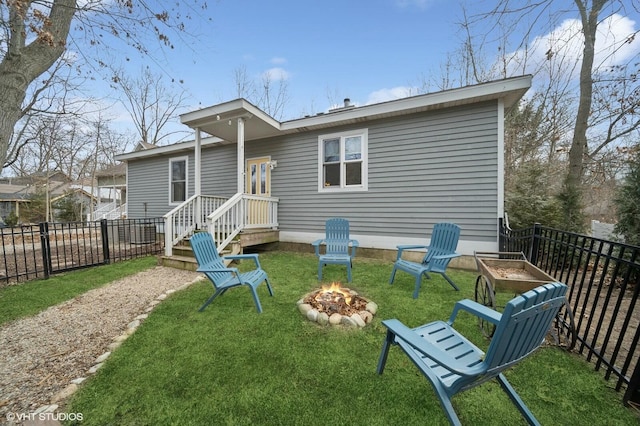 rear view of house featuring a fire pit, a yard, and fence