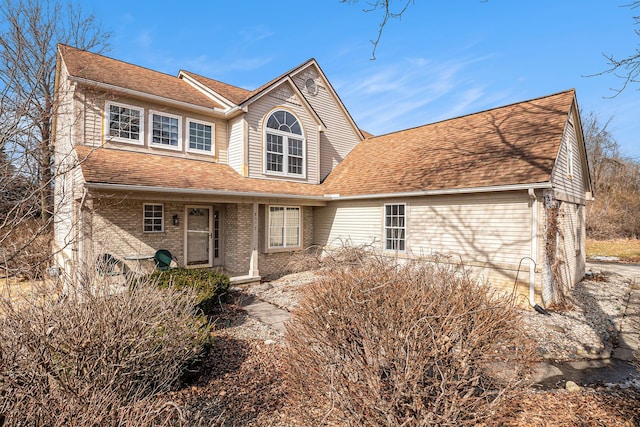 view of front of house with a shingled roof and brick siding