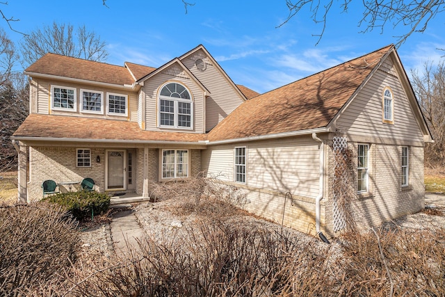 view of front of property featuring a shingled roof and brick siding