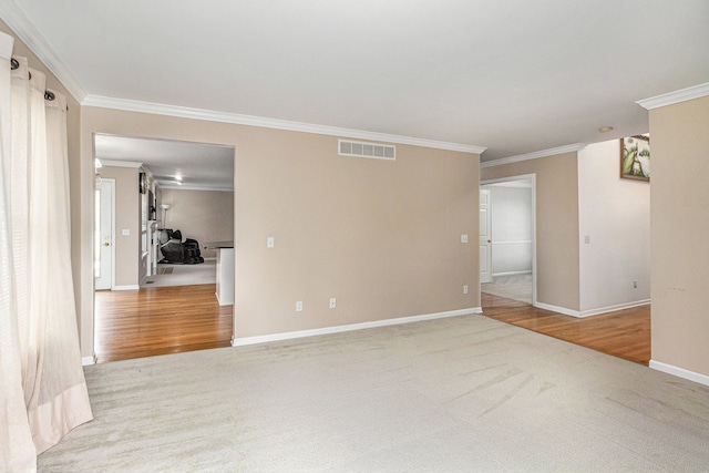 empty room with carpet floors, baseboards, visible vents, and ornamental molding