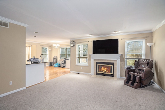 carpeted living area with visible vents, ornamental molding, a tile fireplace, and a wealth of natural light