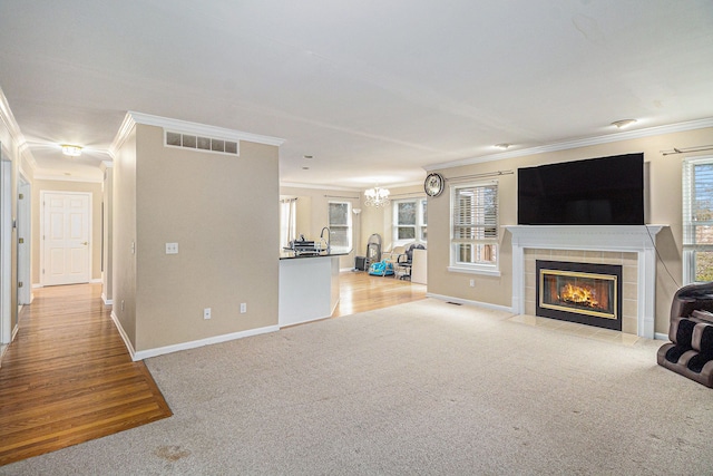 unfurnished living room featuring carpet, a fireplace, visible vents, ornamental molding, and baseboards