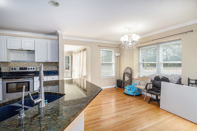 kitchen with tasteful backsplash, ornamental molding, an inviting chandelier, light wood-type flooring, and stainless steel range with electric stovetop