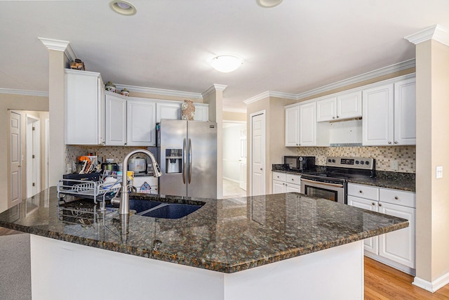 kitchen featuring light wood finished floors, appliances with stainless steel finishes, a peninsula, crown molding, and a sink