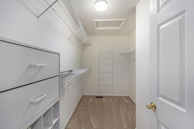 spacious closet with attic access and light carpet