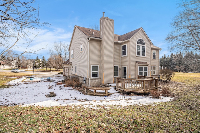 snow covered property with a chimney and a wooden deck