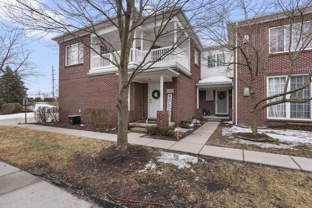 view of front facade featuring a balcony, central AC, and brick siding