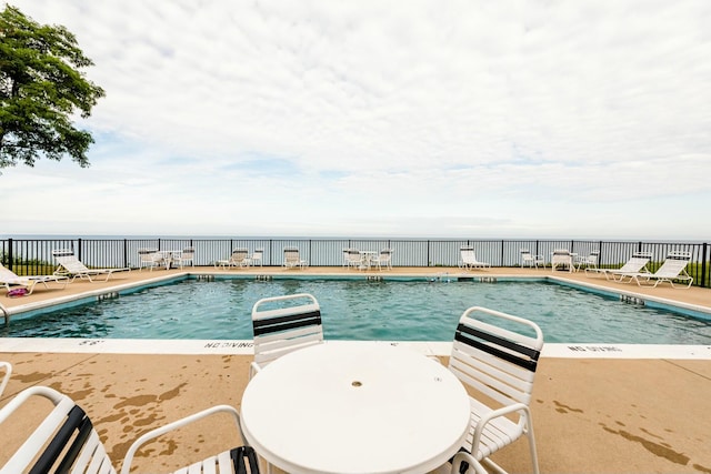 community pool with a patio area and fence