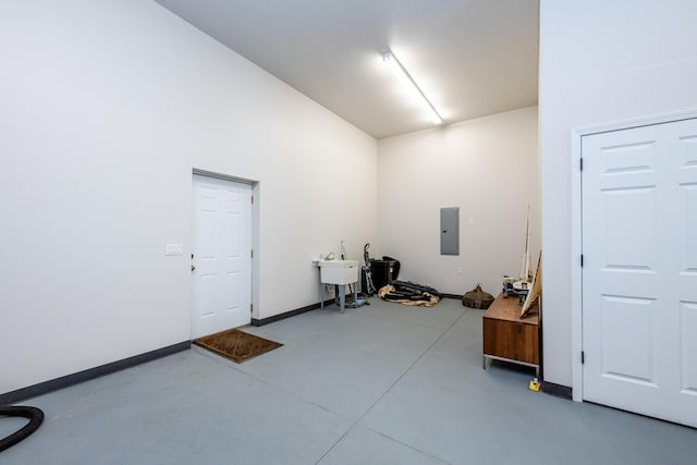 interior space featuring a sink, electric panel, baseboards, and concrete flooring