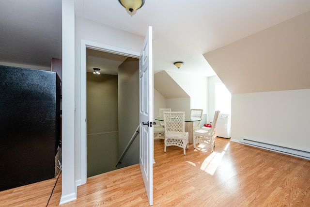 additional living space with lofted ceiling, light wood finished floors, and a baseboard radiator