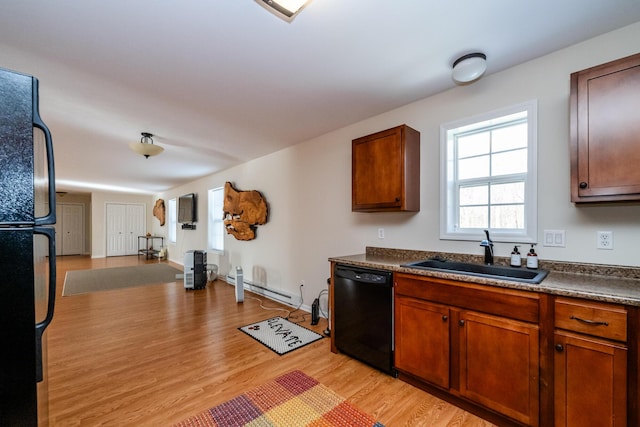 kitchen featuring a baseboard radiator, light wood-style flooring, open floor plan, black appliances, and a sink