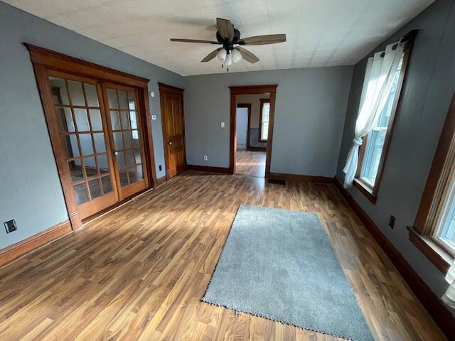 empty room with a ceiling fan, baseboards, and wood finished floors