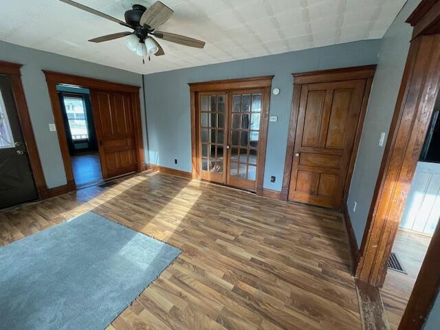 interior space featuring ceiling fan, visible vents, baseboards, and wood finished floors