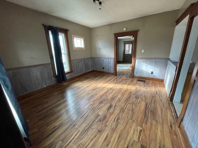 spare room featuring a wainscoted wall, visible vents, and wood finished floors