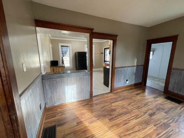 spare room featuring wainscoting, visible vents, and wood finished floors