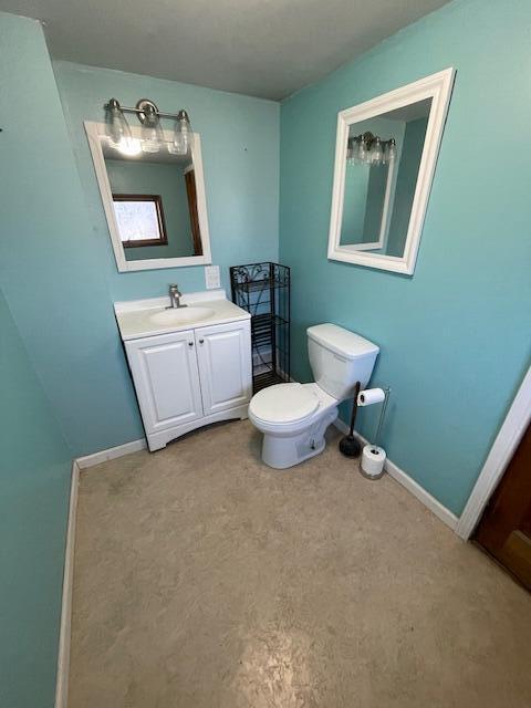 half bath with vanity, toilet, and baseboards