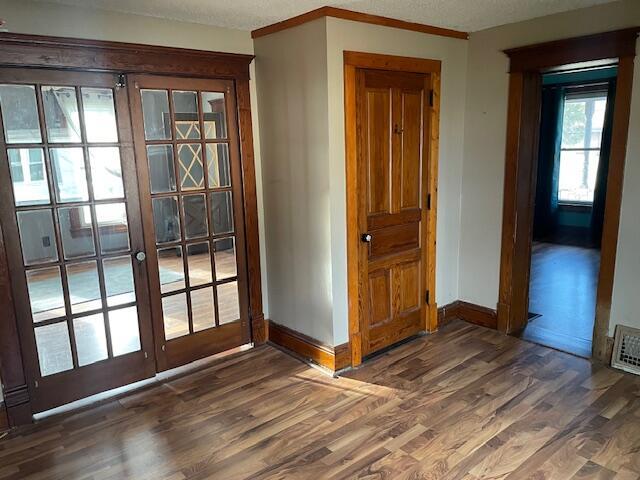 doorway with french doors, crown molding, baseboards, and wood finished floors