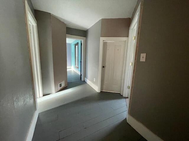 hall featuring baseboards and visible vents