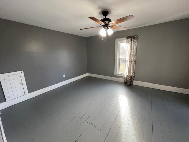 unfurnished room with ceiling fan, dark wood finished floors, and baseboards