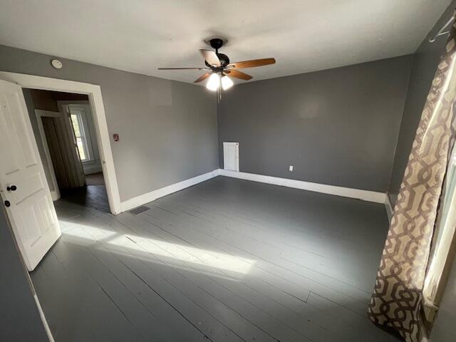 empty room with visible vents, a ceiling fan, hardwood / wood-style flooring, and baseboards