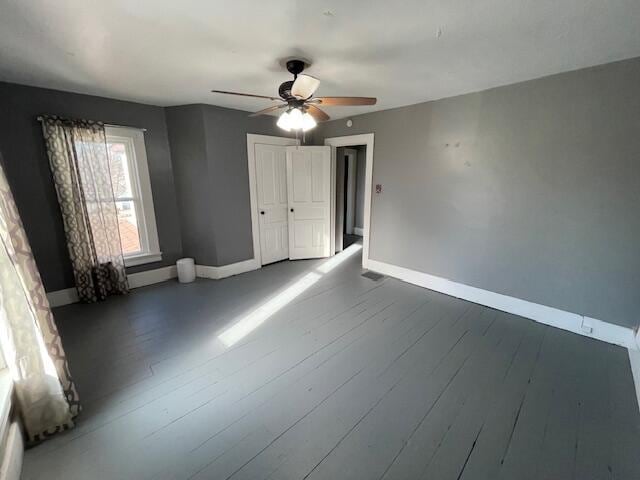 interior space featuring a ceiling fan, wood-type flooring, and baseboards