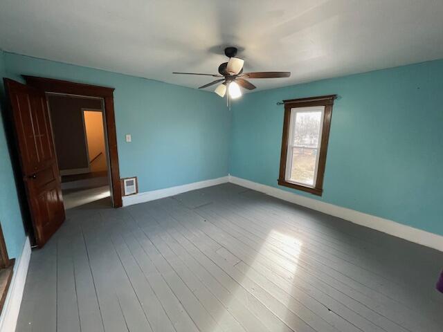 spare room featuring wood-type flooring, baseboards, and a ceiling fan