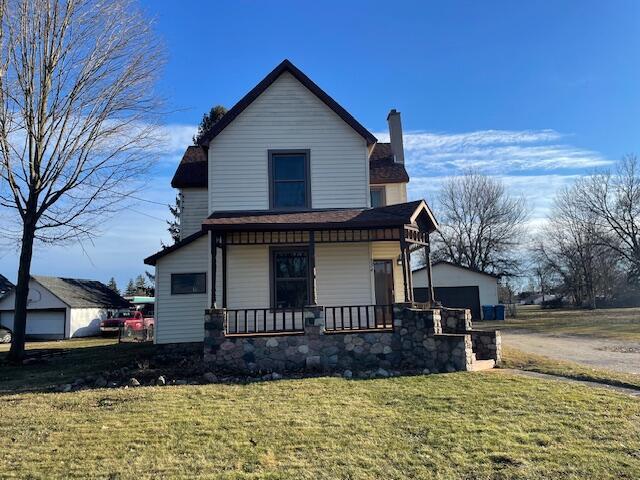 view of front of home with a garage, a chimney, covered porch, an outdoor structure, and a front lawn