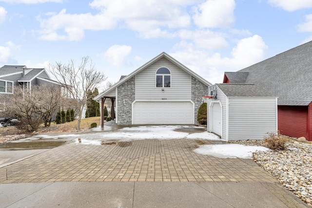 view of front of property featuring decorative driveway, an attached garage, and stone siding