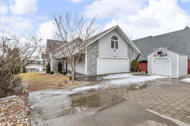 view of side of property with stone siding, driveway, and a shingled roof