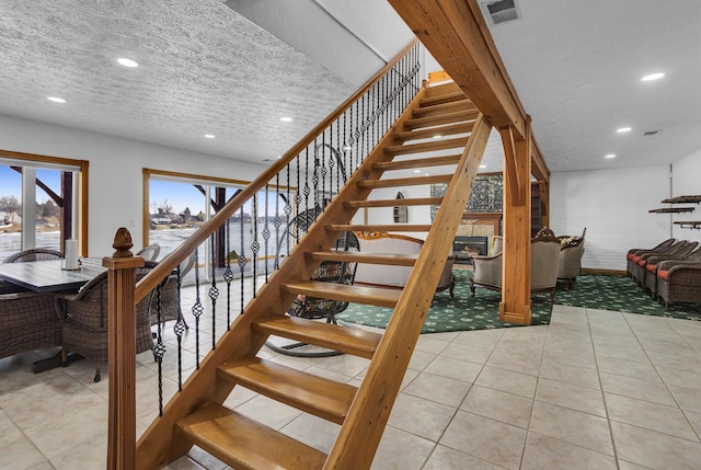 staircase with tile patterned floors, visible vents, recessed lighting, and a textured ceiling