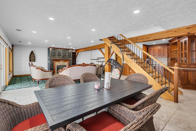 dining area with a textured ceiling, visible vents, a fireplace, recessed lighting, and stairway